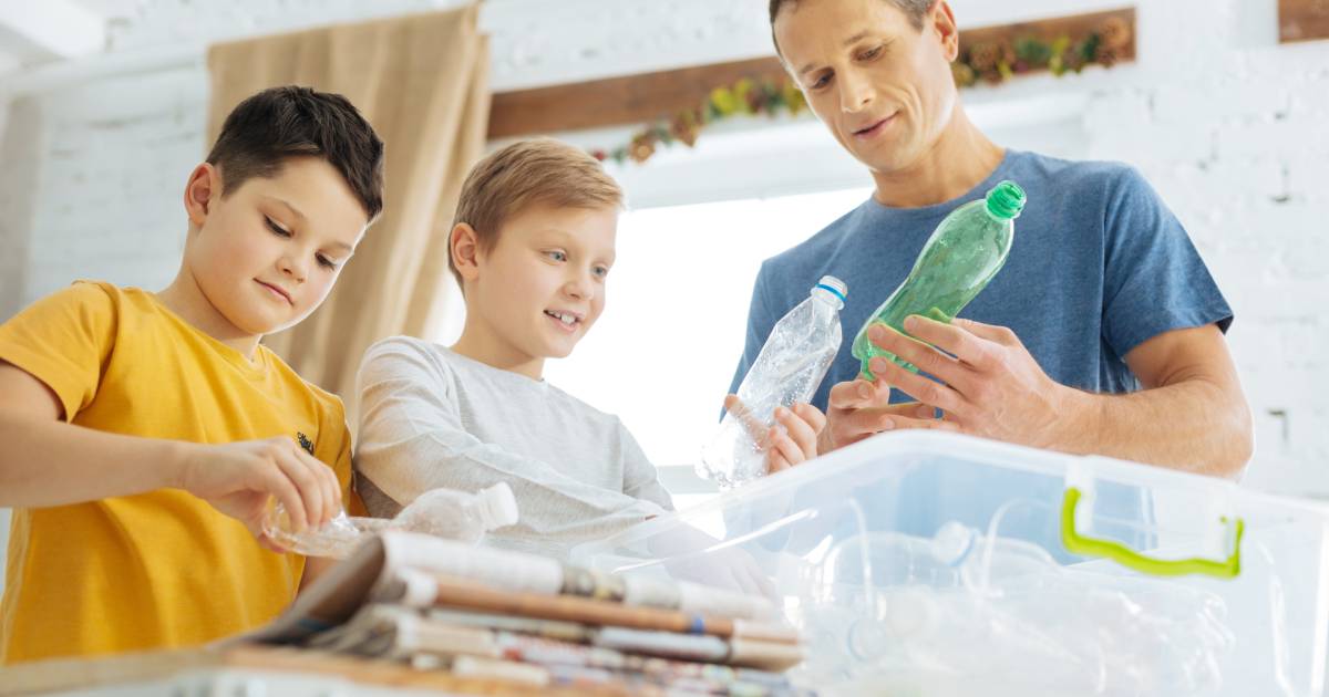 A young father teaching his children about the importance of sustainability by leading a household recycling program.