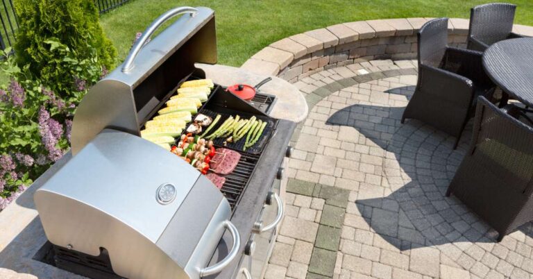 A patio grill with the lid open and fresh foods being cooked, including corn, kabobs, asparagus, and red meat.